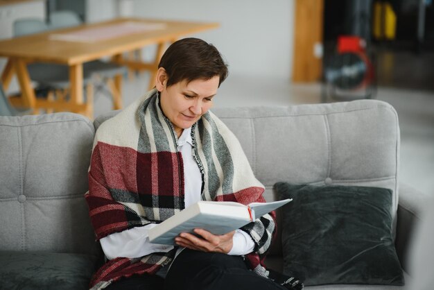 Mulher sênior lendo livro em casa