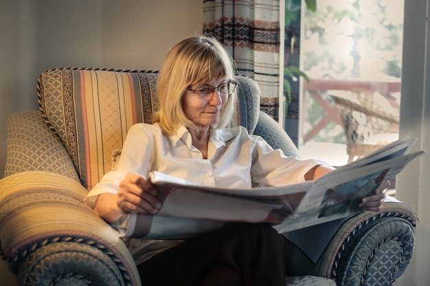 Foto mulher sênior, lendo um jornal