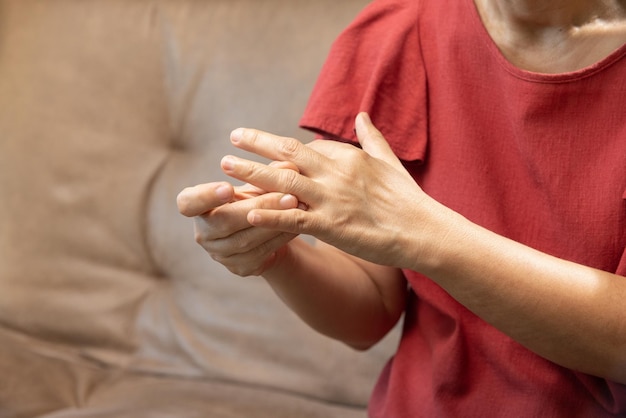 Mulher sênior massageando o dedo com gota inchada dolorosa