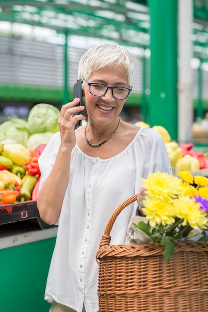 Mulher sênior no mercado usando telefone celular