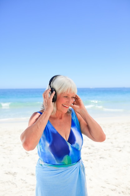 Mulher sênior ouvindo música ao lado do mar