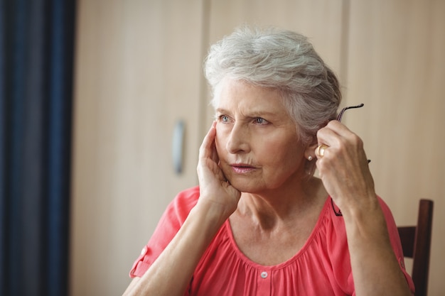 Mulher sênior pensativa, sentado em uma mesa