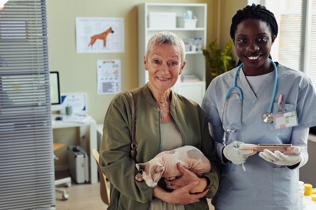 Mulher sênior posando com veterinário na clínica veterinária