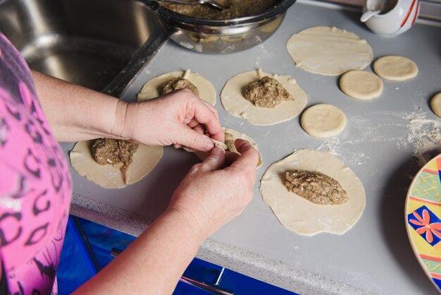 Mulher sênior prepara khinkali.