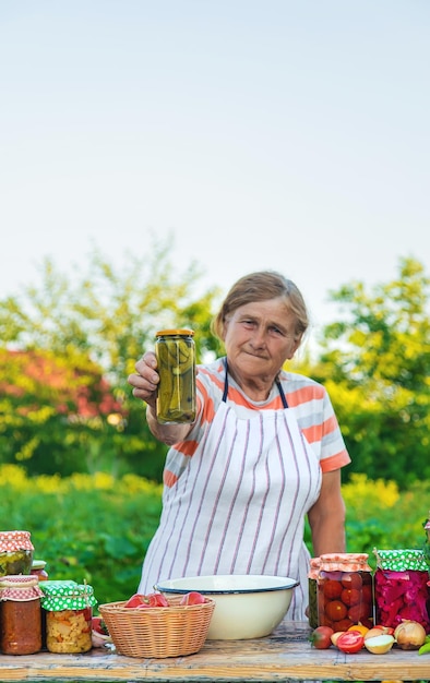 Mulher sênior preservando legumes em potes Foco seletivo