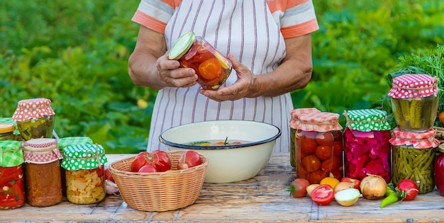 Mulher sênior preservando legumes em potes foco seletivo