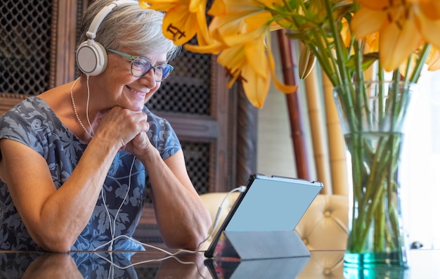 Foto mulher sênior relaxada usando tablet eletrônico com fones de ouvido.