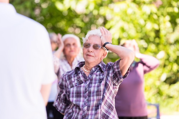 mulher sênior saudável exercitando com amigos na frente do lar de idosos