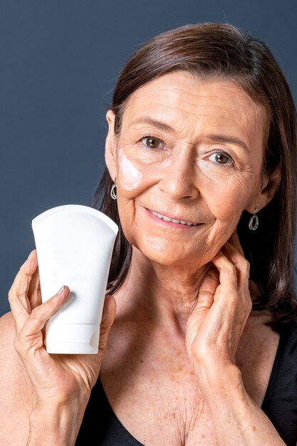 Mulher sênior segurando um tubo de creme facial