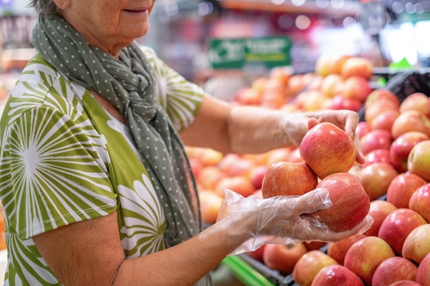 Mulher sênior selecionando frutas frescas de maçã vermelha no conceito de consumismo de supermercado inflação de preços crescente