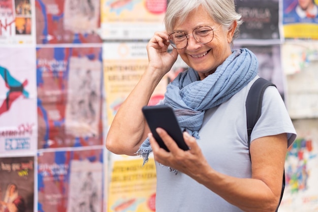 Mulher sênior sorridente atraente andando em sevilha, espanha, usando telefone celular