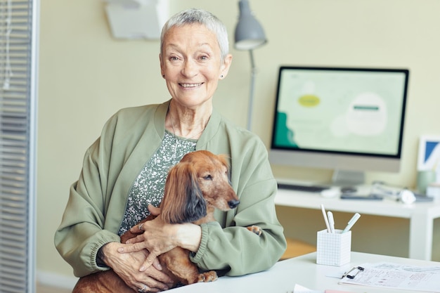 Mulher sênior sorridente com cachorro na clínica veterinária