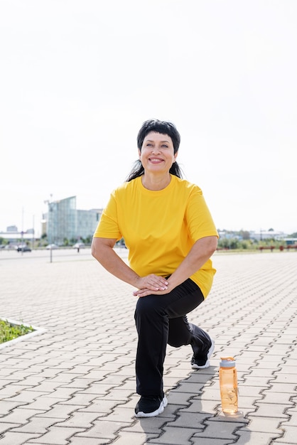 Mulher sênior sorridente se alongando ao ar livre no parque