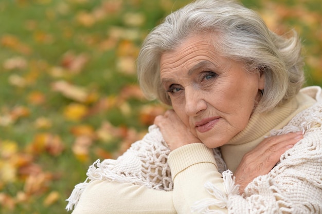 Mulher sênior triste posando no parque outono