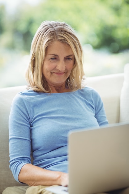 Mulher sênior usando laptop na sala de estar