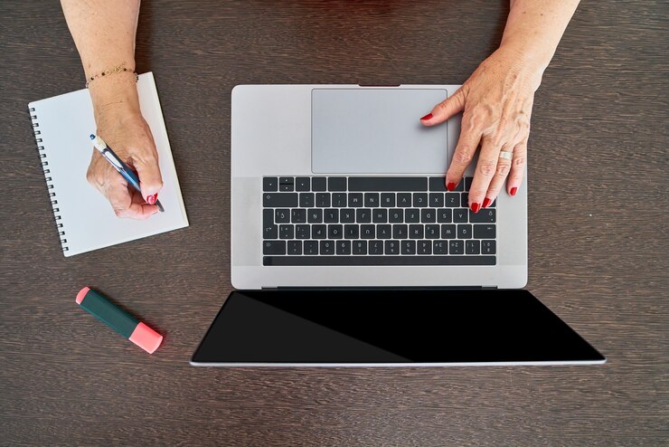 Foto mulher sênior usando o computador no escritório em casa enquanto faz anotações, vista superior