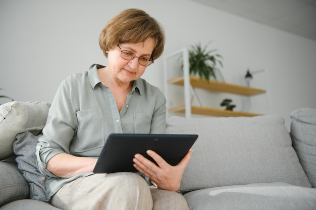 Mulher sênior usando tablet digital na sala de estar em casa