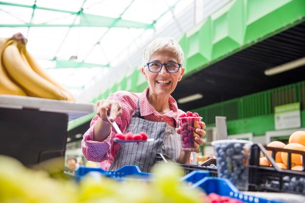 Mulher sênior vende framboesas no mercado