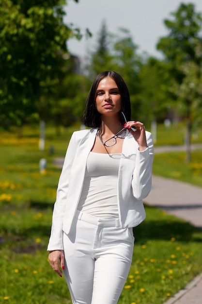 Mulher sensual confiante em elegante terno branco em pé com os olhos fechados e os braços levantados