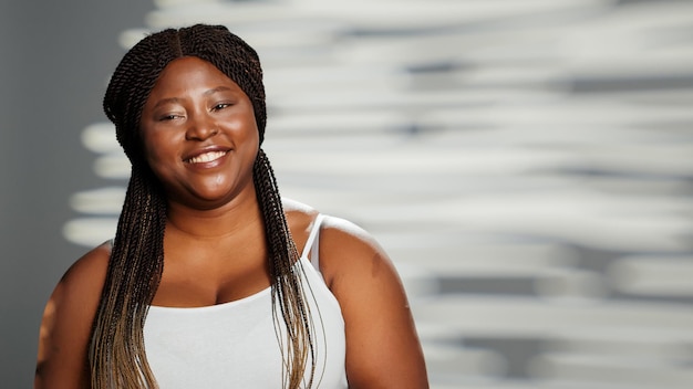 Mulher sensual e glamorosa sendo luminosa na câmera, mostrando autoconfiança e autoaceitação no estúdio. Modelo de beleza jovem expressando positividade corporal em campanha publicitária de cuidados com a pele.