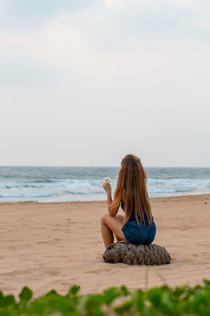 Mulher senta-se pelo oceano