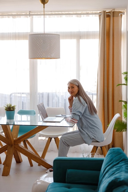 Mulher sentada à mesa com laptop na sala de estar