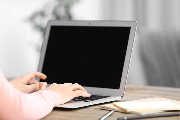 Mulher sentada à mesa trabalhando com um laptop