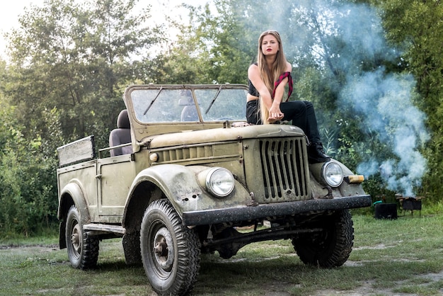 Mulher sentada ao ar livre no capô de um carro militar