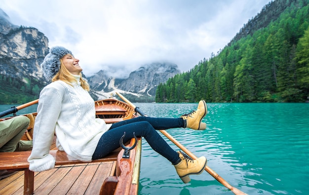 Foto mulher sentada ao lado do lago contra as montanhas