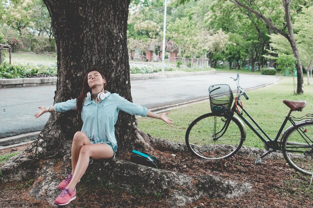 Foto mulher sentada ao lado do tronco da árvore