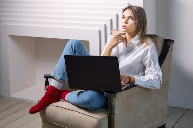 Mulher sentada com laptop durante o teletrabalho dentro de casa
