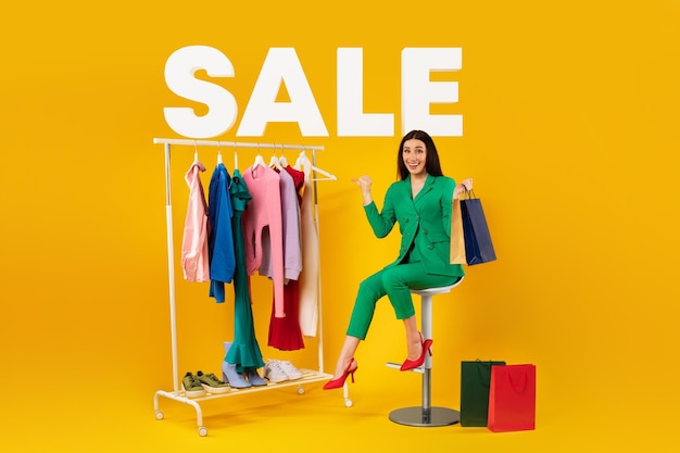 Mulher sentada com sacos de compras apontando para colagem de roupas