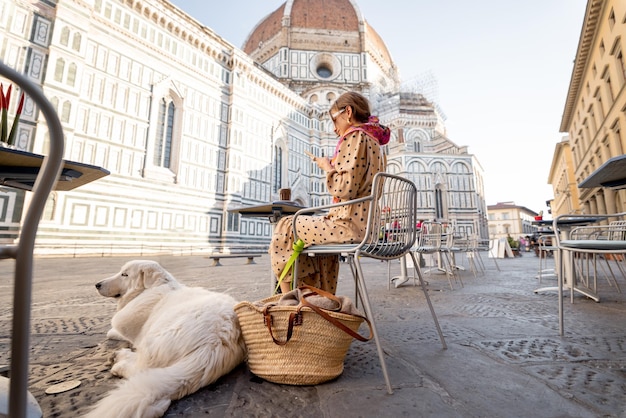 Mulher sentada com seu cachorro no terraço do café perto da famosa catedral duomo em florença
