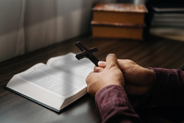 Mulher sentada e estudando as escriturasa cruz de madeira nas mãos conceitos de educação cristã as escrituras sagradas abrem e rezam para deusxa