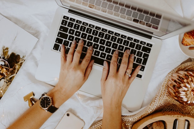 Foto mulher sentada e trabalhando com seu laptop na cama