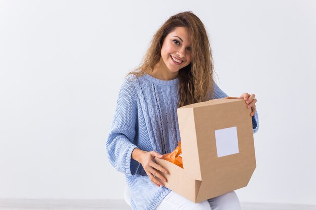 Foto mulher sentada em casa abrindo compra de roupas online