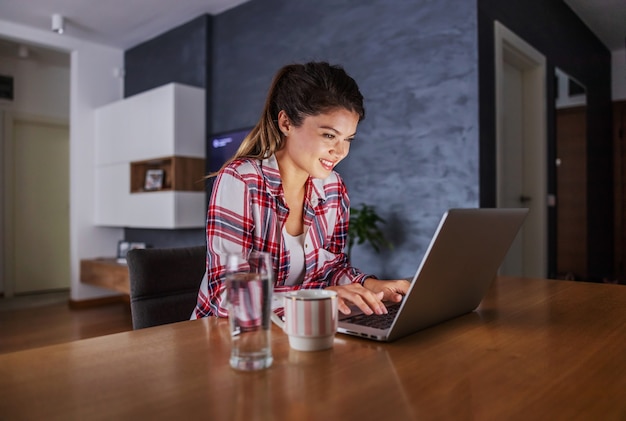 Mulher sentada em casa e usando o laptop para o trabalho. empresa remota durante o surto do vírus corona.