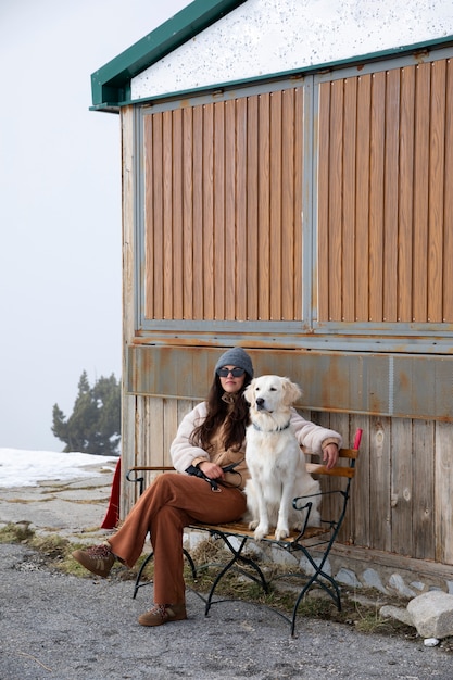 Mulher sentada em um banco com seu labrador durante a viagem de inverno