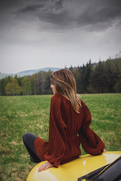 Foto mulher sentada em um carro em tempo de férias nas montanhas, polónia. tempo de primavera