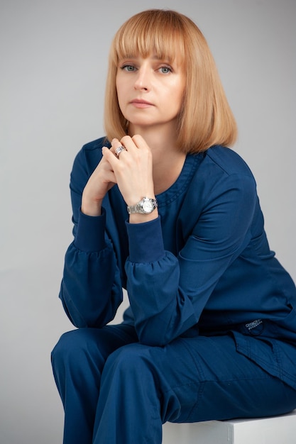 Mulher sentada em um fundo cinza Terno azul escuro formal Doutor pottrait