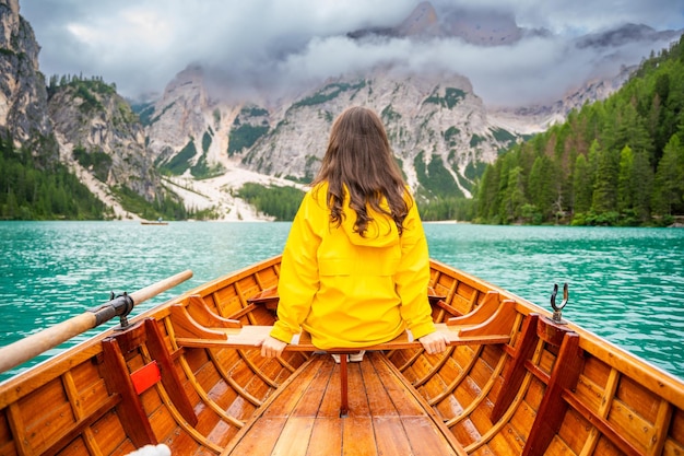 Foto mulher sentada em um grande barco castanho no lago braies em um dia nublado itália férias de verão na europa