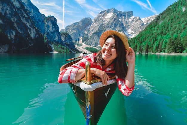 Foto mulher sentada em um grande barco marrom no lago di braies nas férias de verão da itália