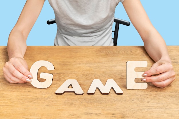 Foto mulher sentada em uma cadeira à mesa apresentou o jogo de palavras de letras de madeira