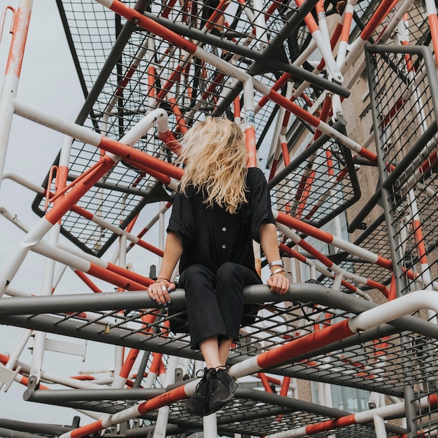 Mulher sentada em uma estrutura construída contra o céu