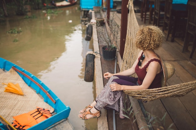 Foto mulher sentada em uma hamaca ao lado do canal