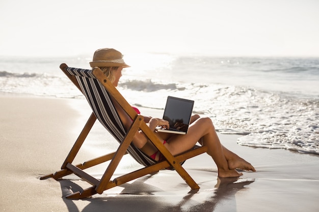 Mulher sentada em uma poltrona e usando um laptop