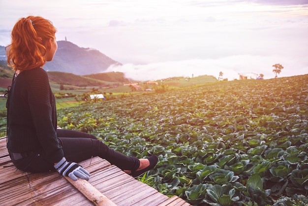 Foto mulher sentada em uma prancha no campo durante o pôr do sol