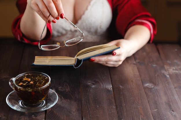 Mulher sentada lendo livro e beber chá