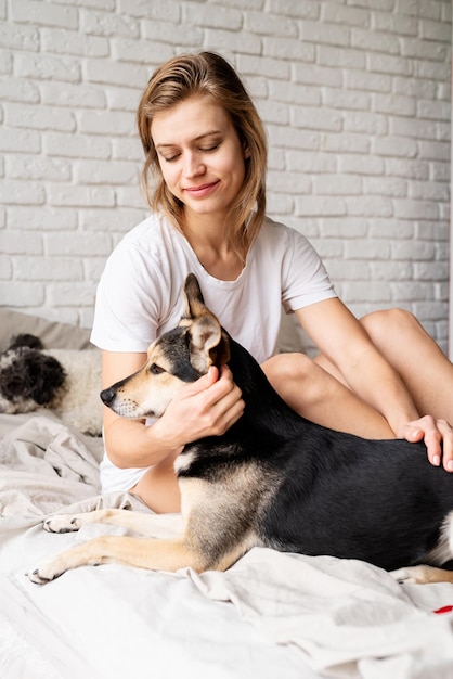 Mulher sentada na cama com seu cachorro engraçado em casa