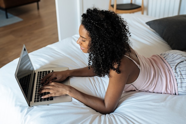 Mulher sentada na cama no computador